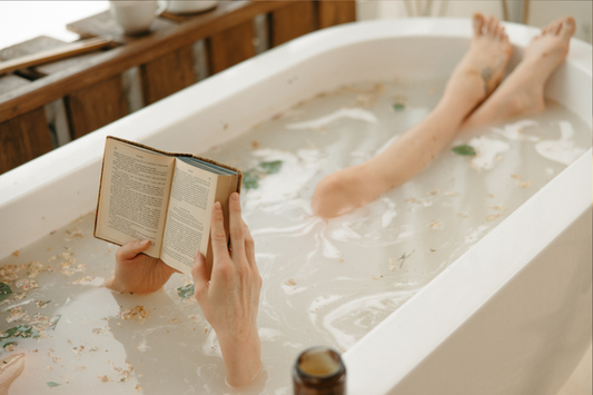 Person reading a book in a bathtub filled with bubbles